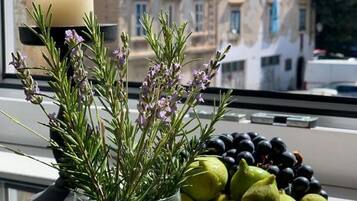 A window with a vase of rosemary and a plate of fruits.