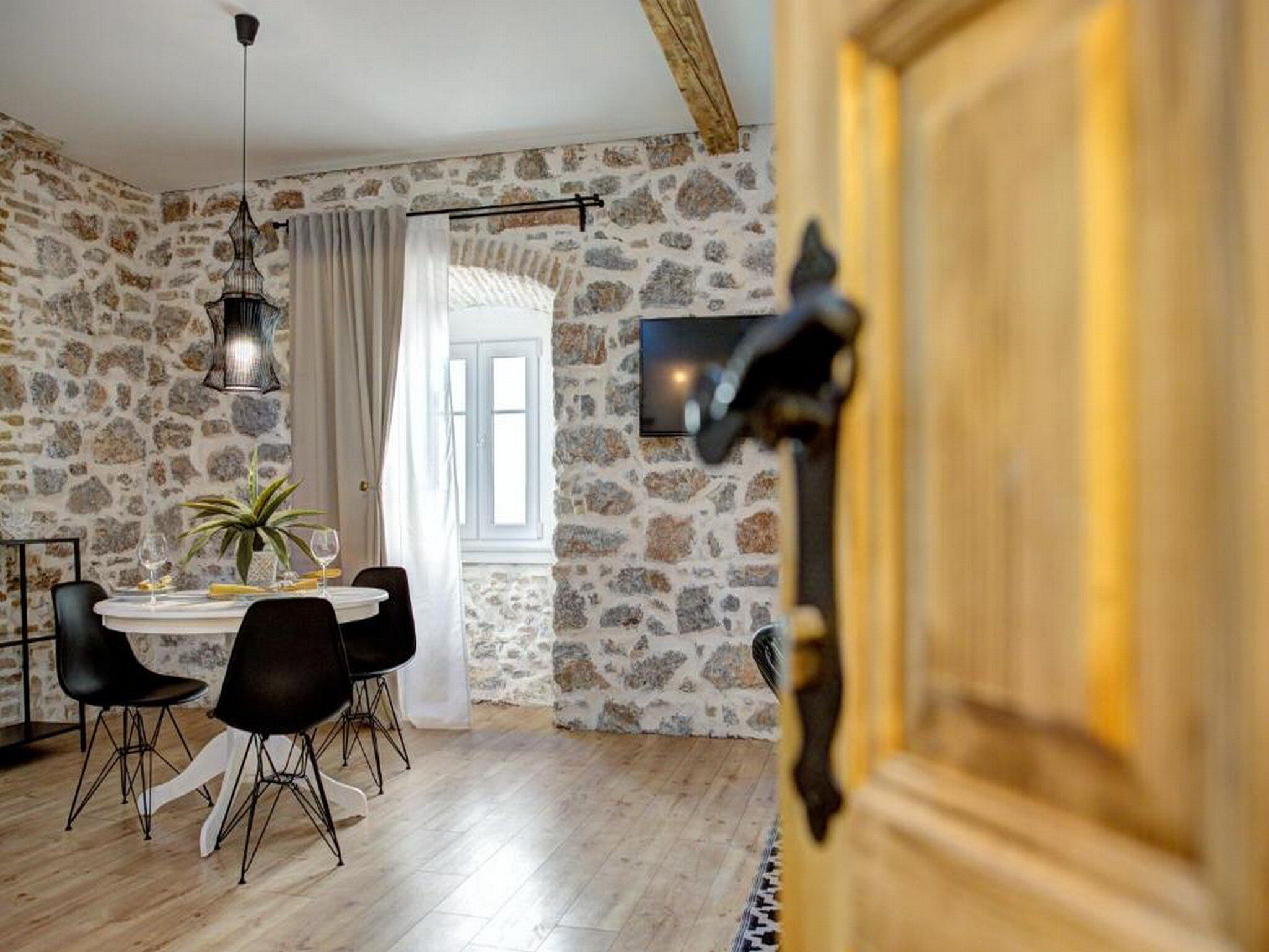 Un comedor con pared de piedra, una puerta de madera y una mesa con sillas.