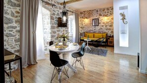 Un comedor con una mesa redonda, dos sillas negras y un sofá amarillo.