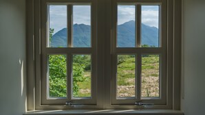 A window with a view of mountains and greenery. - Remote & awe-inspiring Sealgair Cottage. Pet-friendly, log burner, lochside. (Shieldaig)