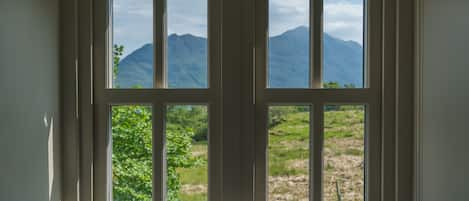 Ein Fenster mit Blick auf Berge und Grün.