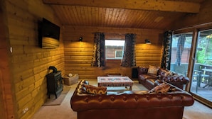 A cozy log cabin interior with a leather sofa, a wooden table, and a fireplace. - Pineshadow Lodge Dog Friendly Kenwick Park Louth (Louth)