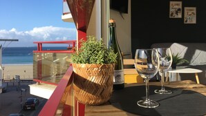 A balcony with a view of the sea, a bottle of wine, two wine glasses, and a woven basket with a plant. - Ideal location for beach and pink granite coast. Sea view from the balcony (Perros-Guirec)