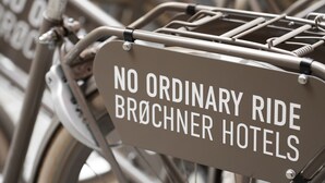 Un vélo portant une pancarte sur laquelle on peut lire : « UNE EXPÉRIENCE UNIQUE, HÔTELS BROCHNER ».