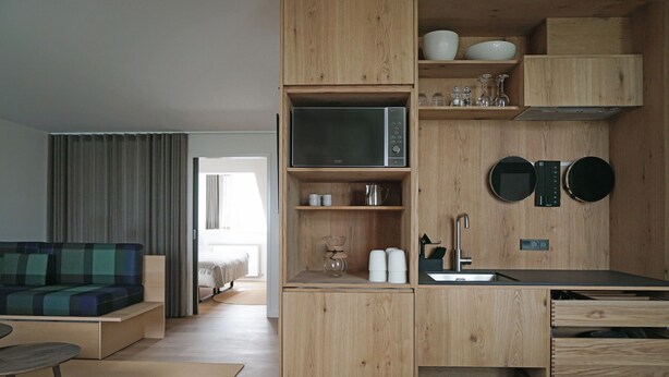 Een kleine keuken met houten kastjes, een magnetron en een spoelbak.
