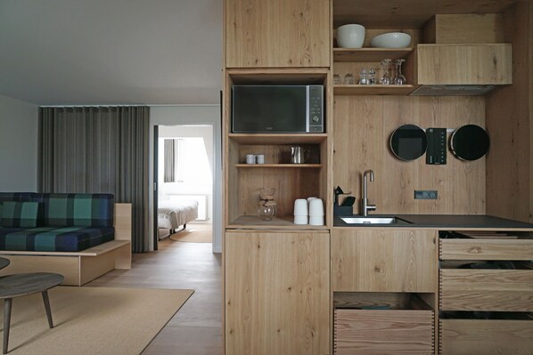 Una cocina compacta con armarios de madera, un microondas y un lavabo.