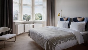 A modern bedroom with a large bed, a desk, and a chair.