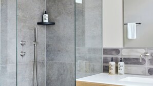Une salle de bain moderne avec une douche à parois de verre, un meuble-lavabo en bois avec un lavabo blanc et un miroir au-dessus du lavabo.