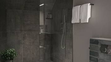 Un baño moderno con ducha de vidrio, inodoro blanco y una planta en maceta.