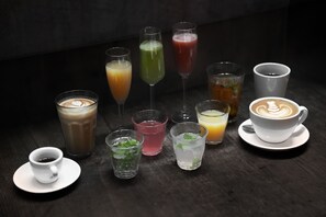 Variedad de bebidas, incluyendo café, té y cócteles, sobre una mesa de madera oscura.