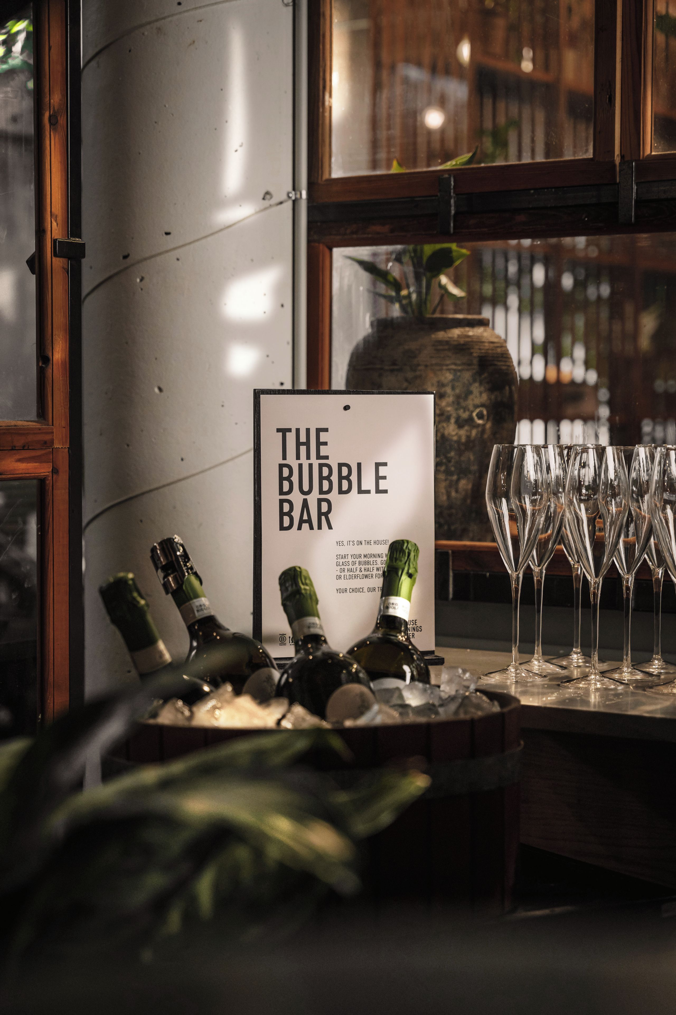 Un área de bar con un cartel que dice 'THE BUBBLE BAR' y varias botellas de champán y copas.