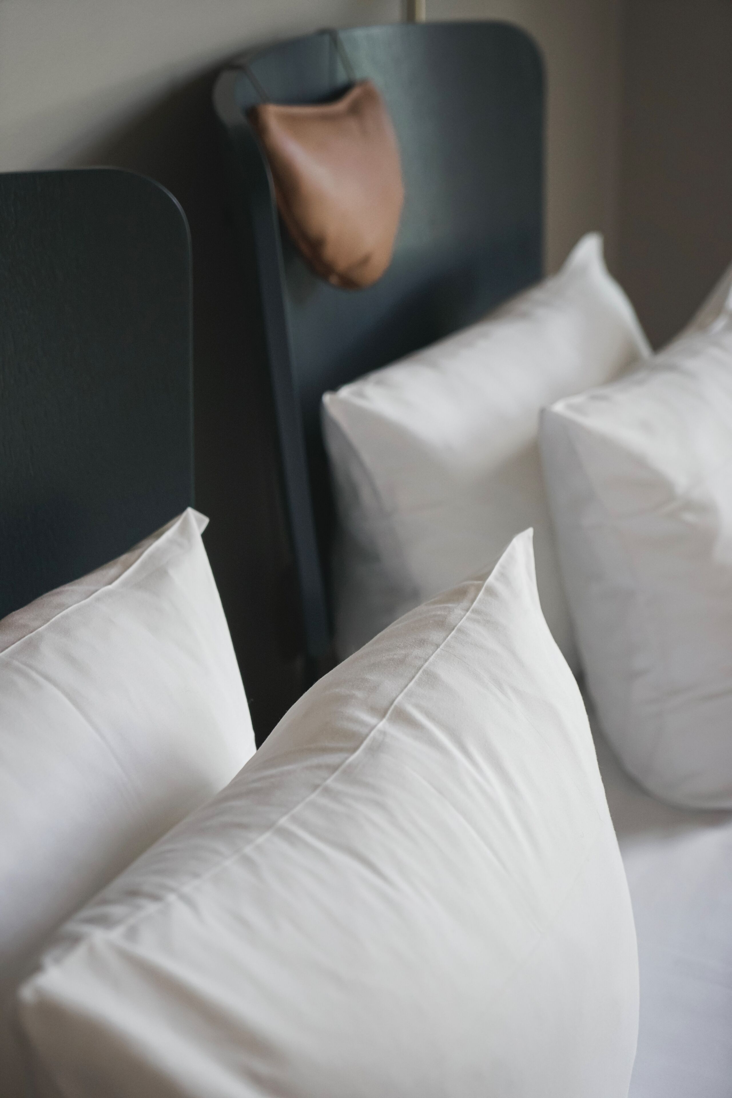 Una cama con almohadas blancas y un cabecero oscuro.