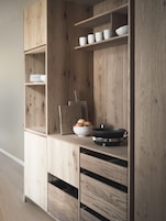 A wooden kitchen cabinet with open shelves, a bowl of fruit, and a frying pan.