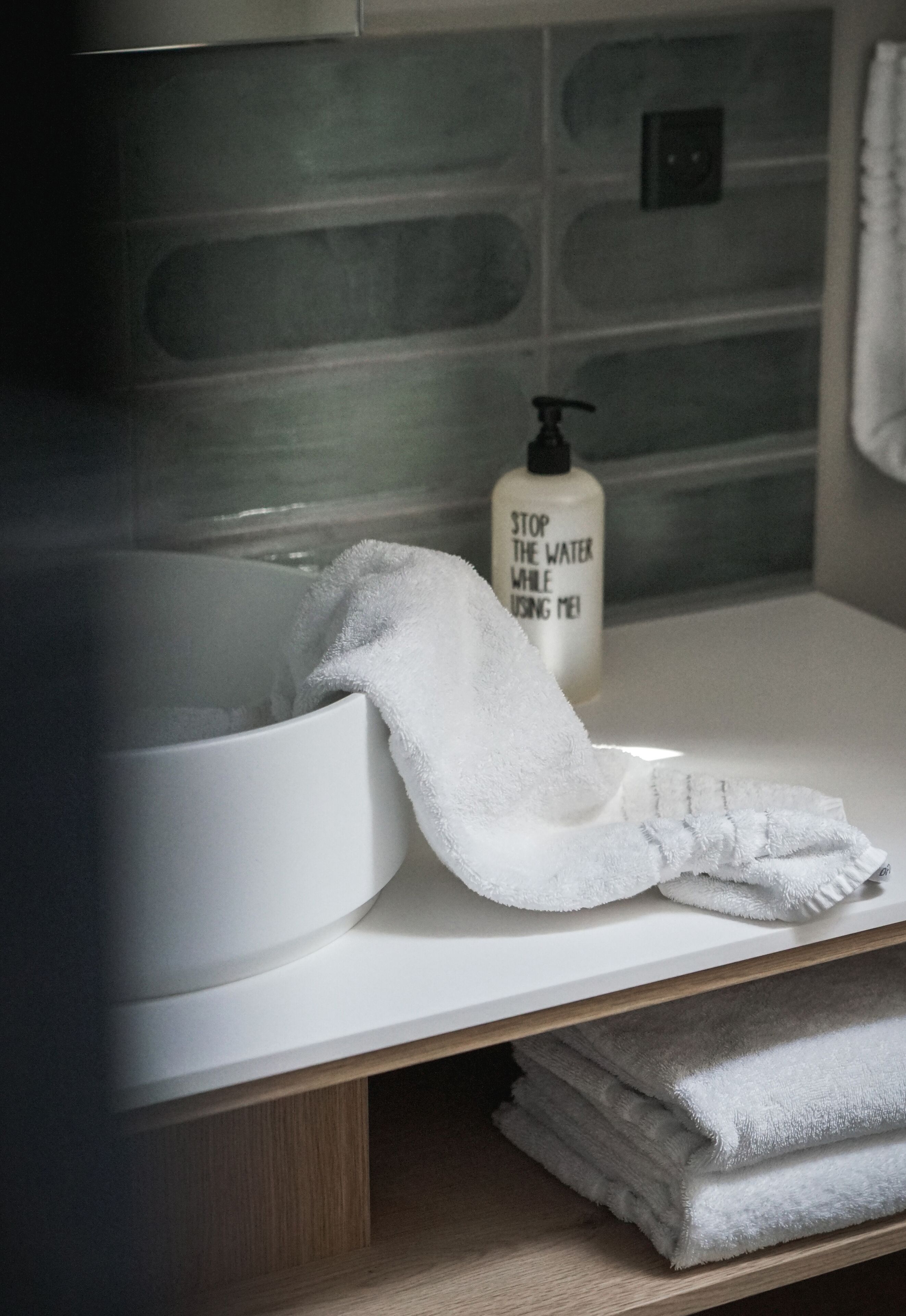 A bathroom with a white sink, a towel, and a soap dispenser.
