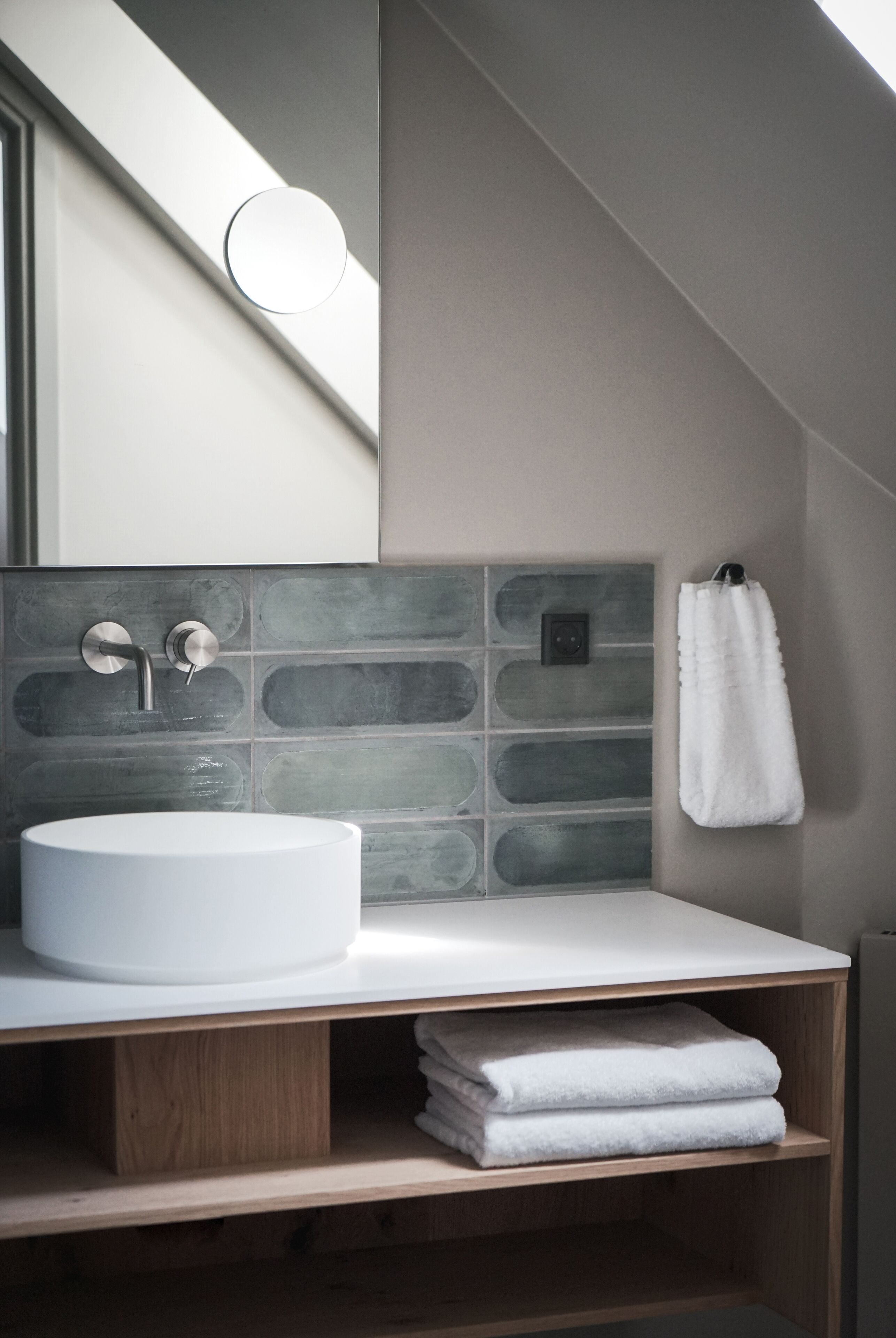 A modern bathroom with a large white sink, a mirror, and a towel rack.