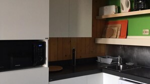 A modern kitchen with white cabinets, a black microwave, a sink, and a coffee maker on a green shelf. - 10m from ski slopes, 10th floor, balcony, tv, 28m², Les Arcs (Les Arcs)