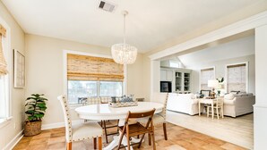 A dining area with a round table, chairs, and a chandelier. There is a potted plant and a wicker basket on the floor. - Private Canal Home w/ Boat Dock, 2 Living Areas - Fish from the Deck! (Galveston)