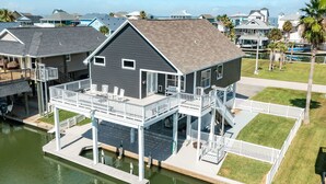 A waterfront house with a deck, a covered outdoor area, and a view of the water. - Private Canal Home w/ Boat Dock, 2 Living Areas - Fish from the Deck! (Galveston)