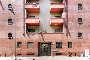 Un edificio de ladrillo rojo con un patio central, balcones y una entrada con reja.