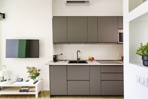 Una cucina moderna con mobili grigi, un rubinetto nero e un piano di lavoro bianco.