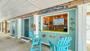 A coastal-themed bar with turquoise chairs and a sign reading "Drift Away Shores." - Drift Away Shores · Steps to the beach!*Week Discount*Tiki Bar*2 Pools (Gulf Shores)