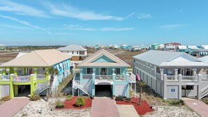 A beachfront hotel with multiple colorful buildings, a beach entrance, and a clear view of the ocean. - Drift Away Shores · Steps to the beach!*Week Discount*Tiki Bar*2 Pools (Gulf Shores)