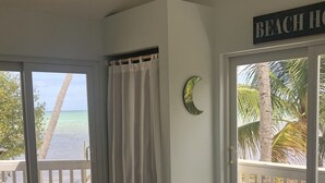 A bedroom with a large bed, a view of the beach, and a sign reading "BEACH HOUSE".