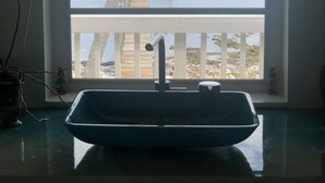 A bathroom with a window overlooking a wooden dock and water.