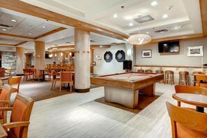 Une salle de billard équipée de tables, de chaises et d’un billard.