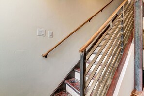 A staircase with a wooden handrail and metal balusters, leading to a landing with a white wall and two light switches. - Beaver Run Resort Ski-in/Ski-out & walk to Main St (Breckenridge)