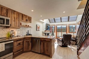 Une cuisine moderne avec des meubles en bois, un four à micro-ondes encastré et un grand îlot central doté d’un évier.