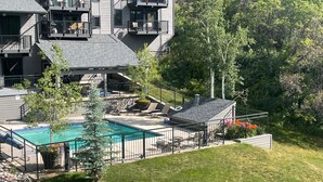 A modern building with a swimming pool, outdoor seating, and a landscaped garden.