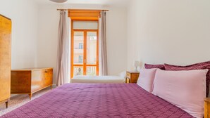 Ein Schlafzimmer mit einem großen Bett, einer hölzernen Kommode und einem Fenster mit Vorhängen.