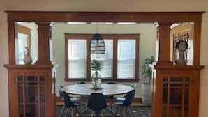 A dining area with a round table, black chairs, and a decorative hanging light fixture.