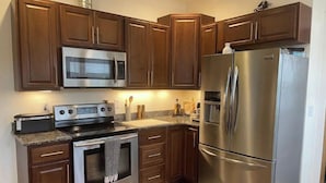 A modern kitchen with stainless steel appliances, wooden cabinets, and granite countertops.