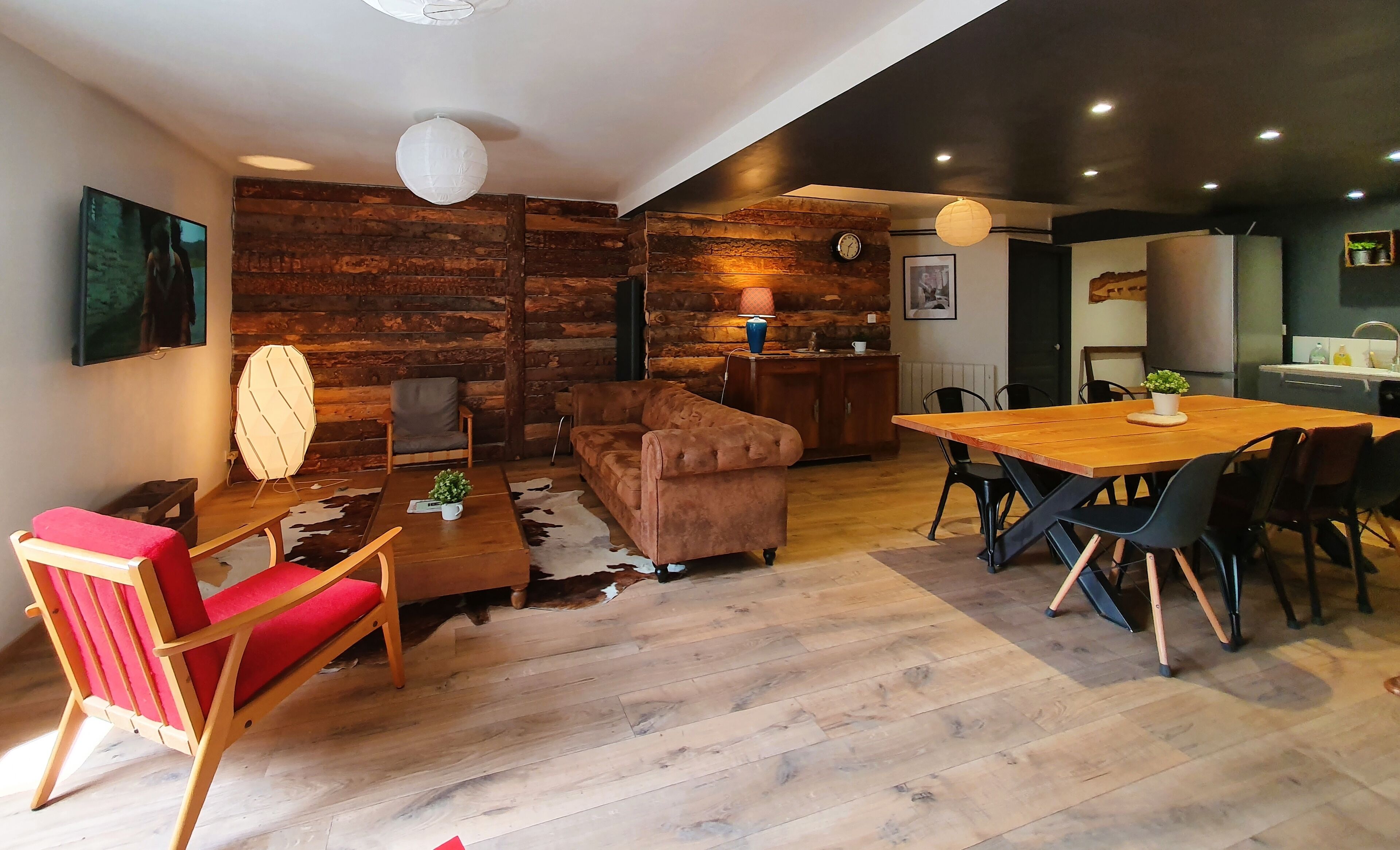 Una sala de estar moderna con una pared de madera, un sofá, una mesita de centro y un comedor con sillas.