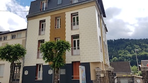 Ein mehrstöckiges Gebäude mit einer beige-weißen Fassade, zahlreichen Fenstern und einem dunklen Dach.
