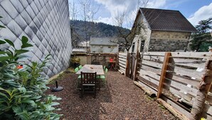 Ein Gartenbereich mit Holztisch und -stühlen, umgeben von einem Holzzaun und einer Steinmauer.