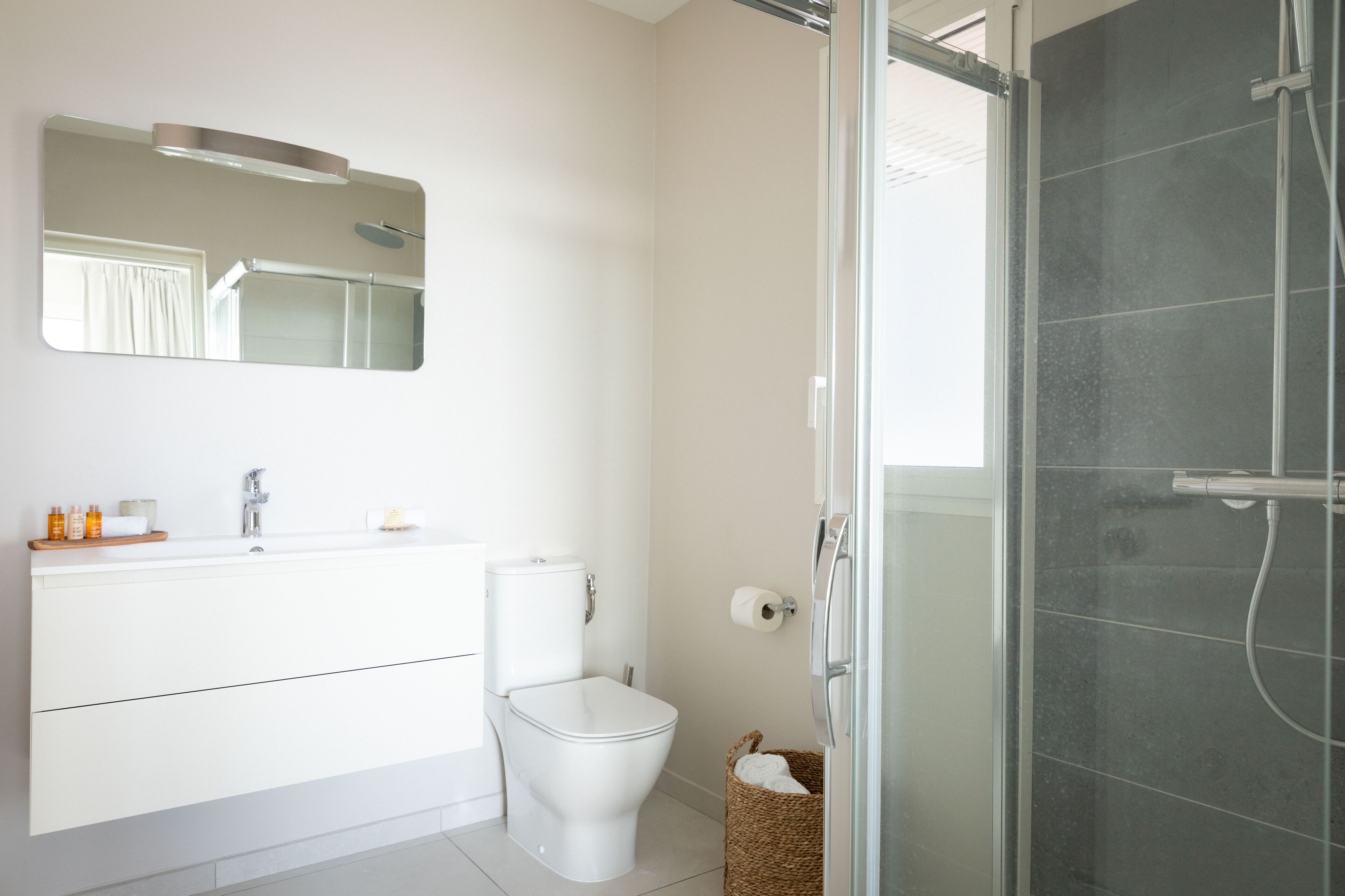A modern bathroom with a toilet, sink, and shower.