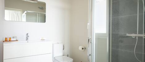 A modern bathroom with a toilet, sink, and shower.