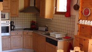A kitchen with wooden cabinets, a microwave, a coffee maker, a toaster, and a sink. - Spacious chalet 10 ppl, southeast, pets allowed (Valloire)