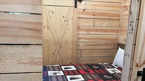 Una stanza piccola con rivestimenti in legno e un letto con una coperta patchwork.