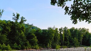 A calm river with clear water reflecting trees and a rocky shore.