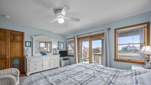 Ein Schlafzimmer mit Bett, Kommode, Fernseher und Blick ins Freie.