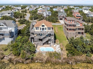A coastal residential area with houses, a swimming pool, and a view of the ocean. - 7680- Sandy Bottom. Avon Beach Retreat | Pool & Hot Tub (Avon)