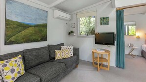 A modern living room with a grey sofa, a flat-screen TV, and a painting of a landscape.