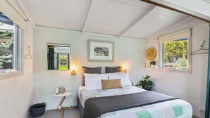 A bedroom with a bed, bedside table, lamp, and a window with a view.