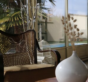 A room with a large window, a wicker chair, a white vase with dried plants, and a white birdcage. - Quiet villa between the lake and the sea in Hourtin, with a pool and spa (Hourtin)