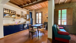 A cozy kitchen with blue cabinets, a wooden dining table, and a stone wall. - Panicale 7 - Three Bedroom Apartment, Sleeps 6 (Firenze)