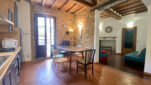 A rustic kitchen with a wooden table and chairs, a stone wall, and a tiled floor. - Panicale 7 - Three Bedroom Apartment, Sleeps 6 (Firenze)